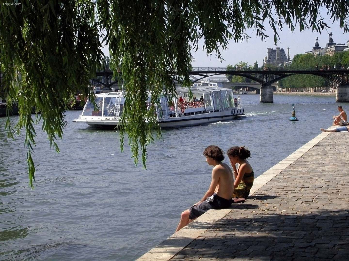 Đôi bạn trẻ ngồi tắm nắng trên công viên đảo le Vert Galant, Paris