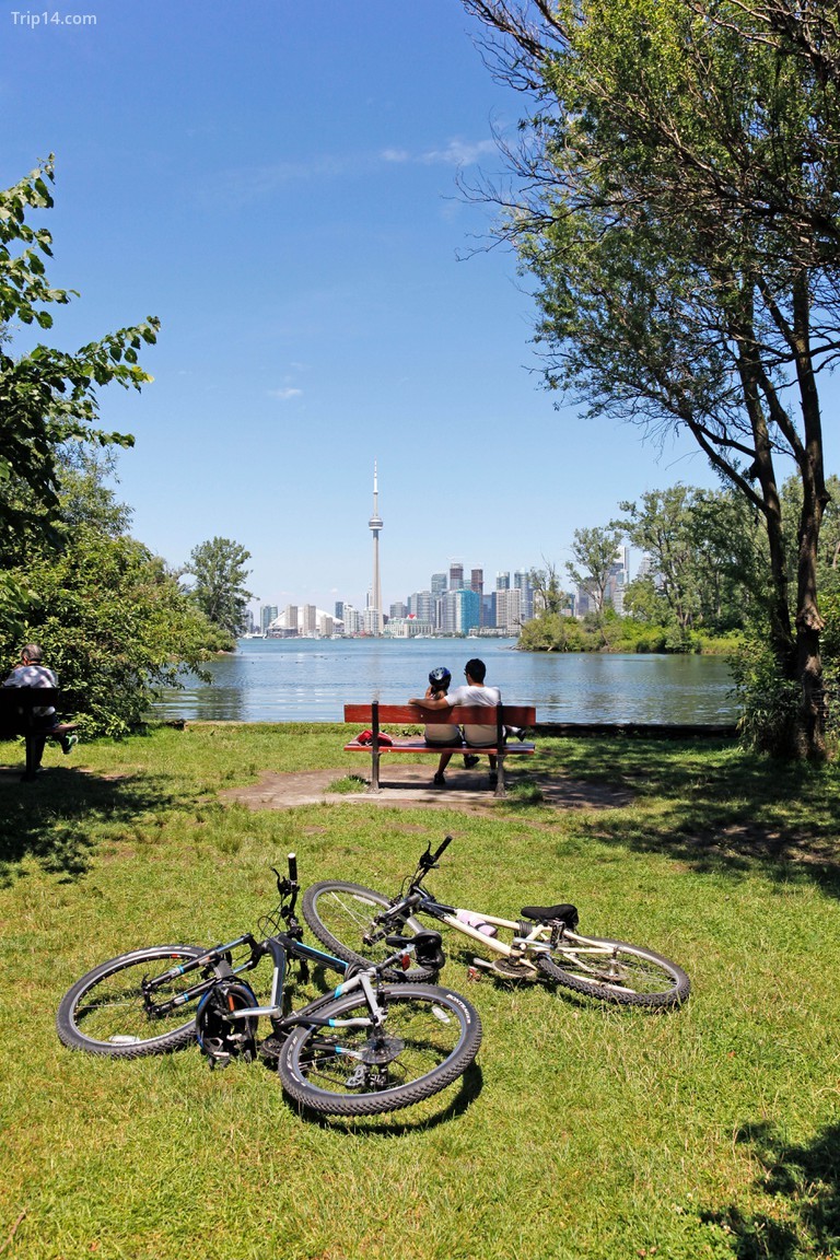 Cặp đôi thu vào tầm mắt sau khi đạp xe đến Công viên đảo Center với đường chân trời ở phía sau, hồ Ontario. - Trip14.com