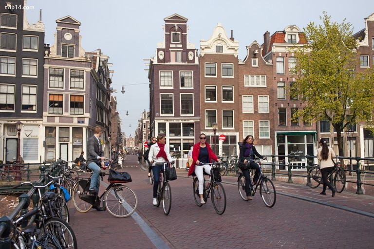 Amsterdammers đi xe đạp qua cầu kênh Singel ở thành phố Amsterdam, Hà Lan. - Trip14.com