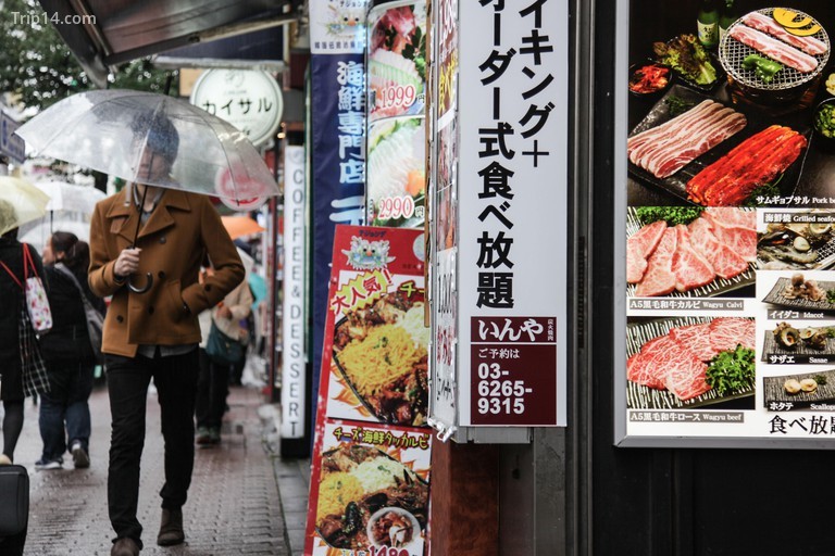 Một người đàn ông với chiếc ô đi ngang qua thức ăn đường phố ở Thị trấn Hàn Quốc, ga Shin-okubo, Tokyo, Nhật Bản. - Trip14.com